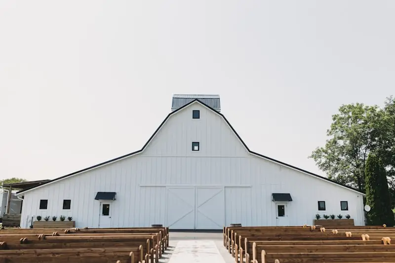 Rows of wooden pews set for a ceremony inside a barn.
